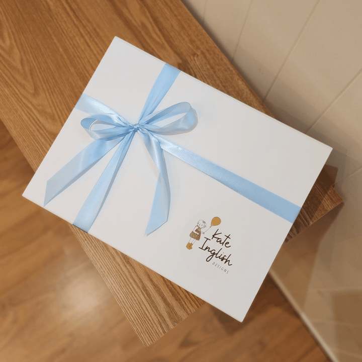 A white baby hamper box with satin blue ribbon